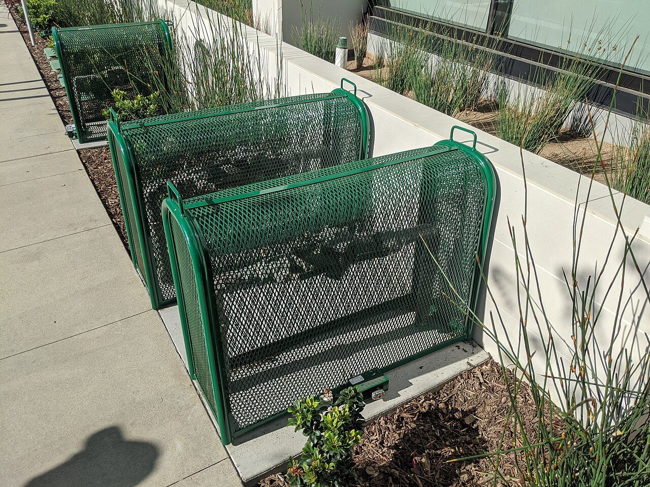 Protected backflow preventer cages installed along a landscaped walkway