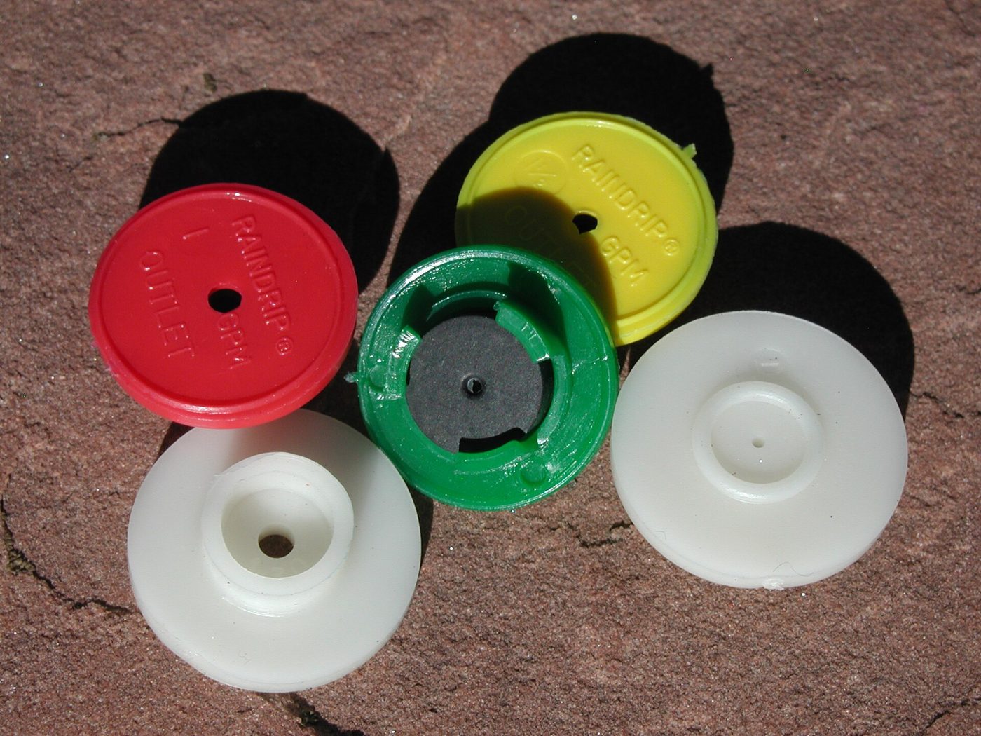 Raindrip irrigation emitters and drip fittings on a patio surface
